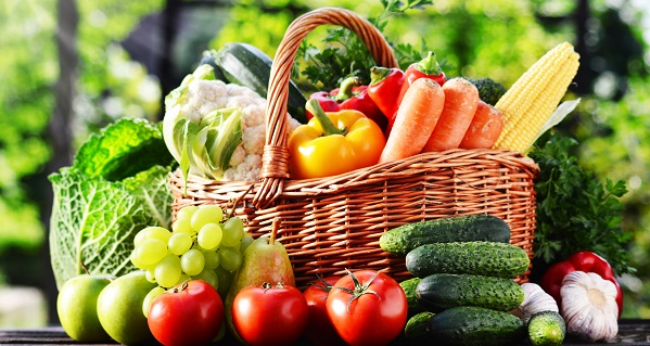 Wicker basket with assorted raw organic vegetables in the garden.